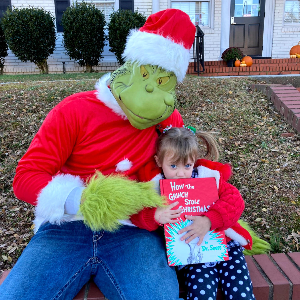 A little girl holds her "How the Grinch Stole Christmas" book while getting her photo with the Grinch himself at the annual Holiday Hop in Travelers Rest, SC.