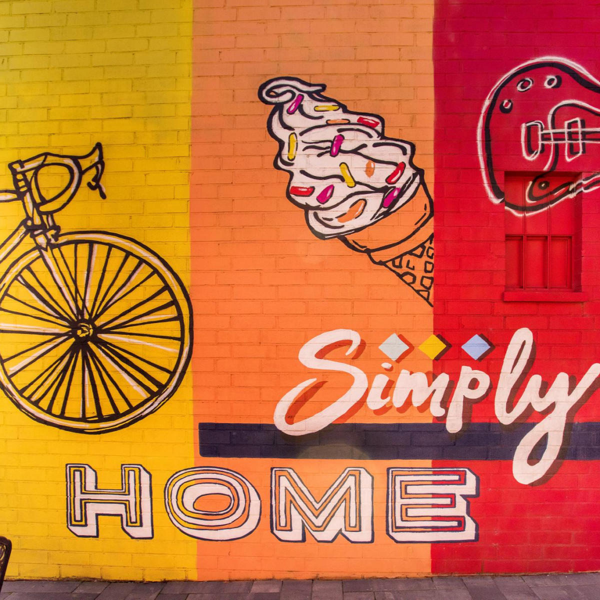 A yellow, orange, and red mural that says "Simply Home" on it, located in Simpsonville, SC.