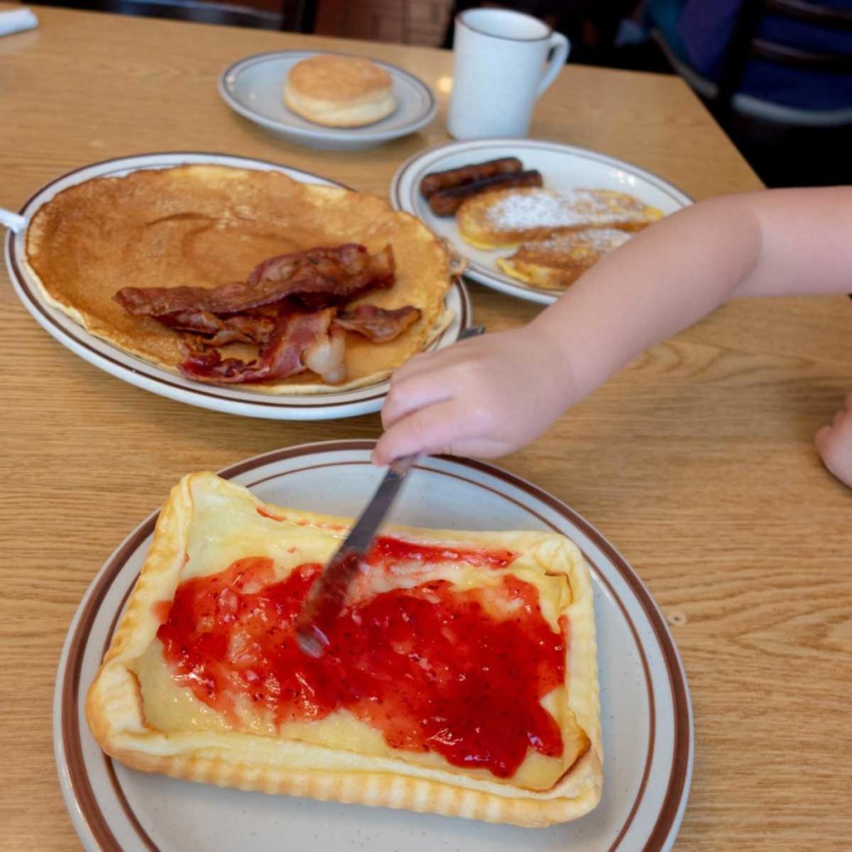 Rasberry jam being spread on finnish pancakes.