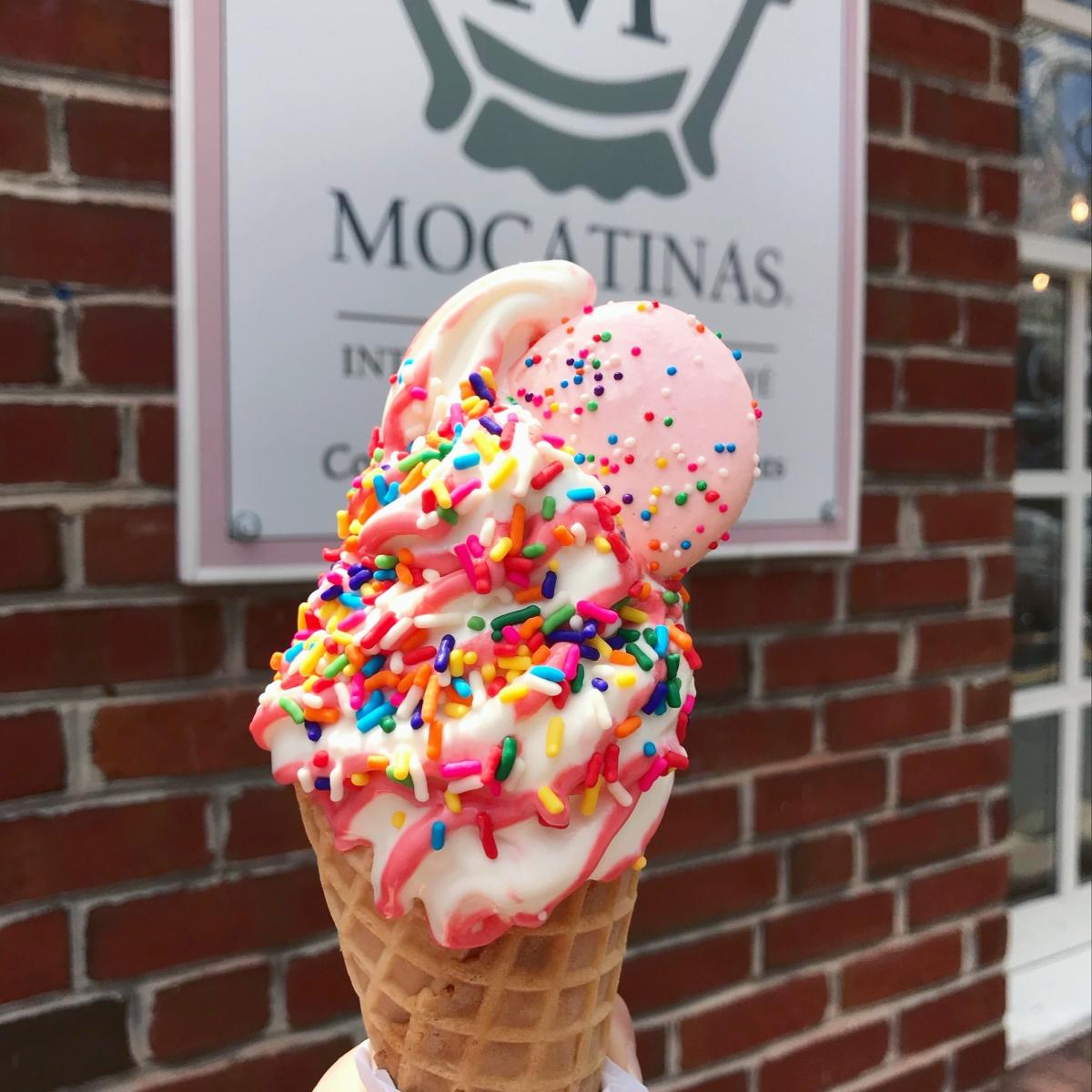 Mocatinas Ice cream in a waffle cone with a cookie and rainbow sprinkles on top