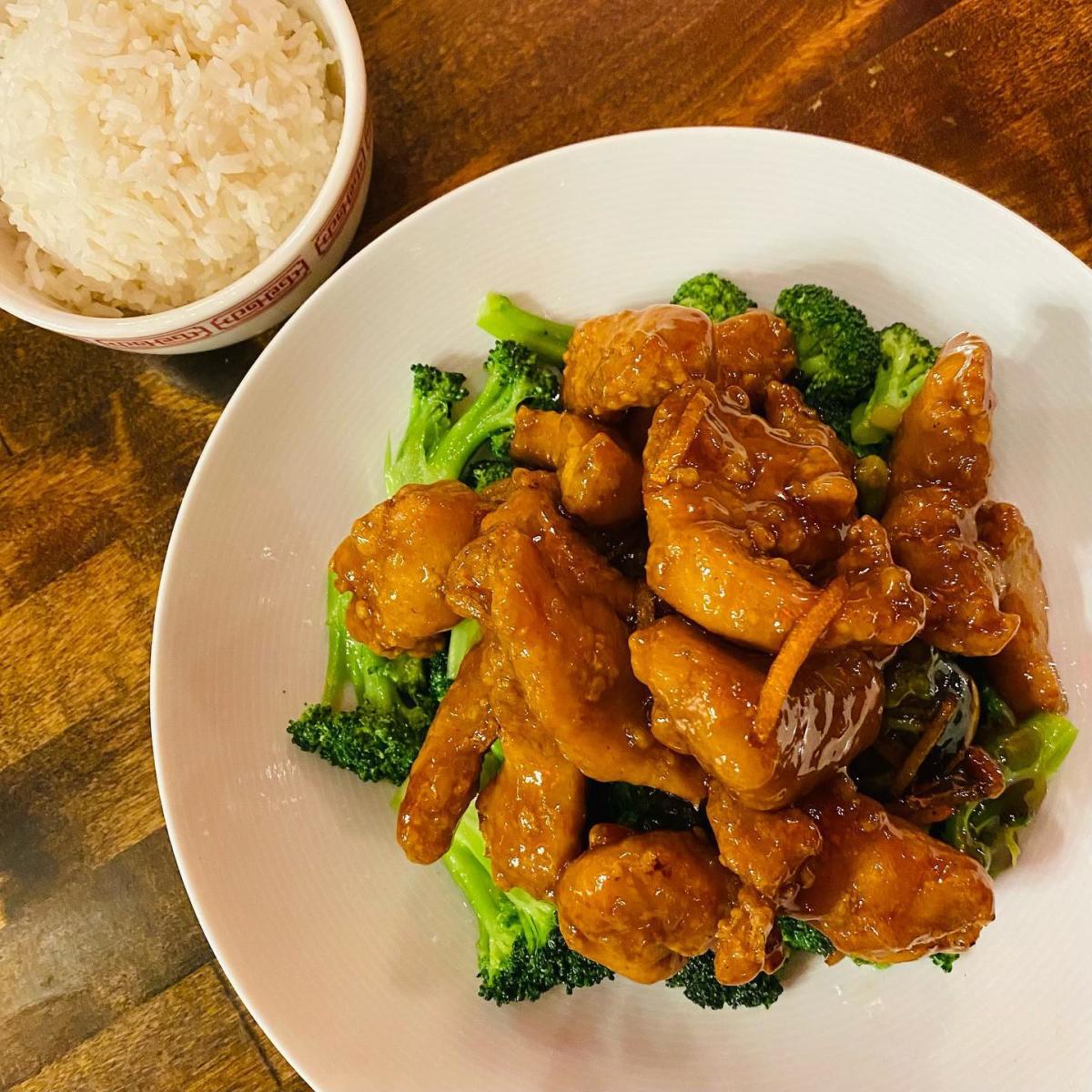 Orange chicken on a bed of broccoli and white rice on the side at Little Palace