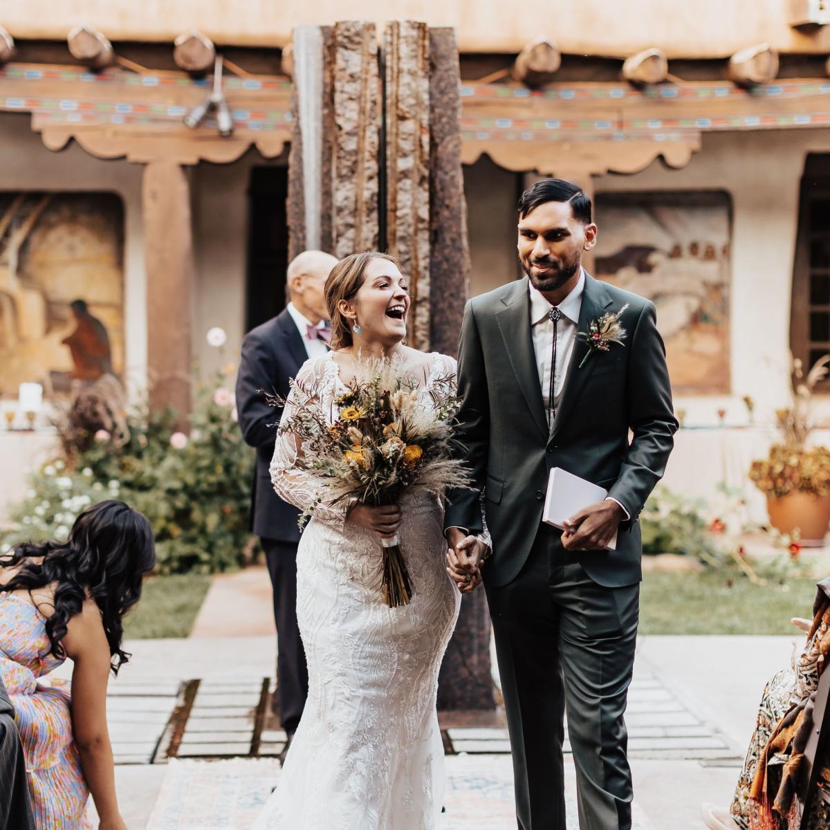 Bride and groom walking hand-in-hand after wedding ceremony at the New Mexico Museum of Art.