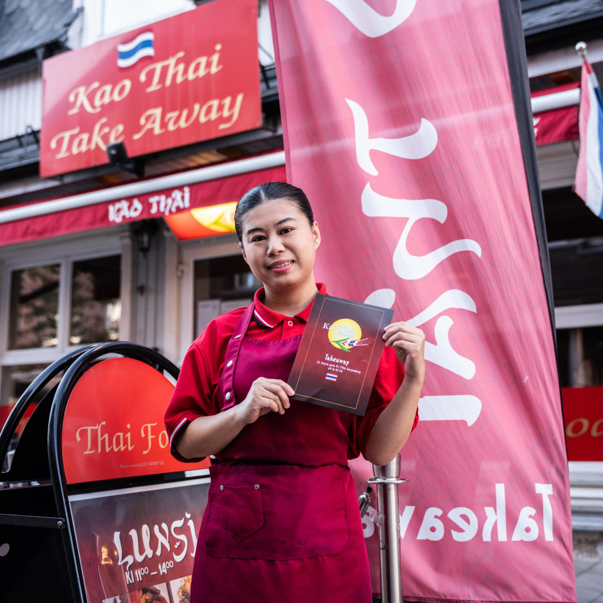 Kvinne som holder en meny i hånda utenfor Kao Thai. Foto.