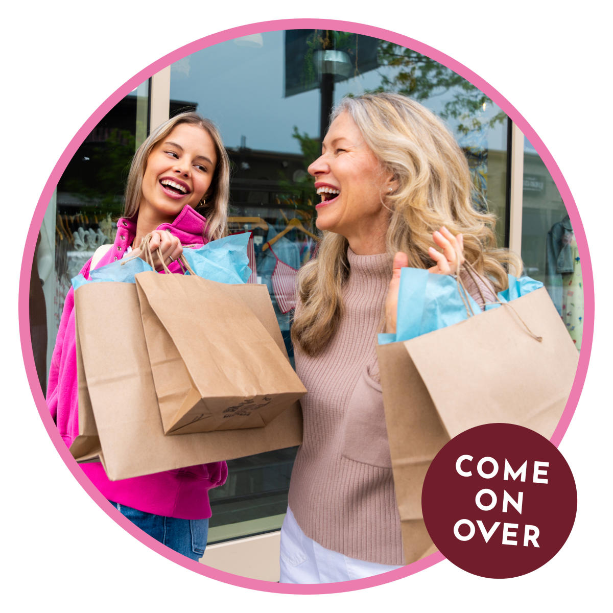 A blonde mother laughs while carrying shopping bags beside her smiling daughter as they shop in Overland Park.