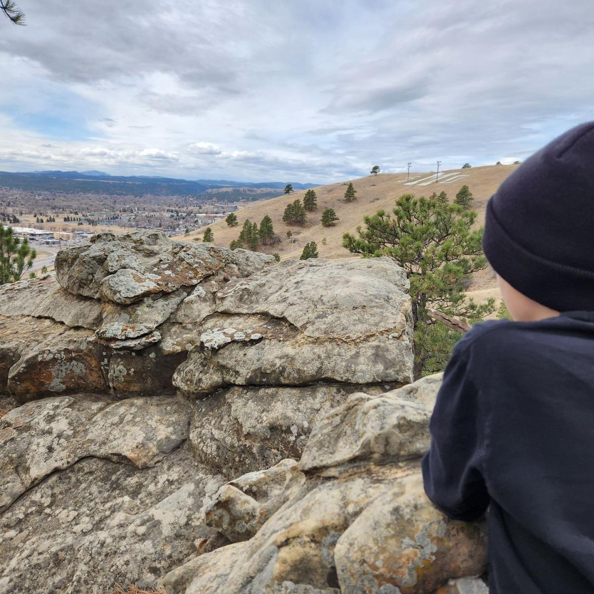 kid looking out over the rocks at the M on M Hill and views of Rapid City, SD
