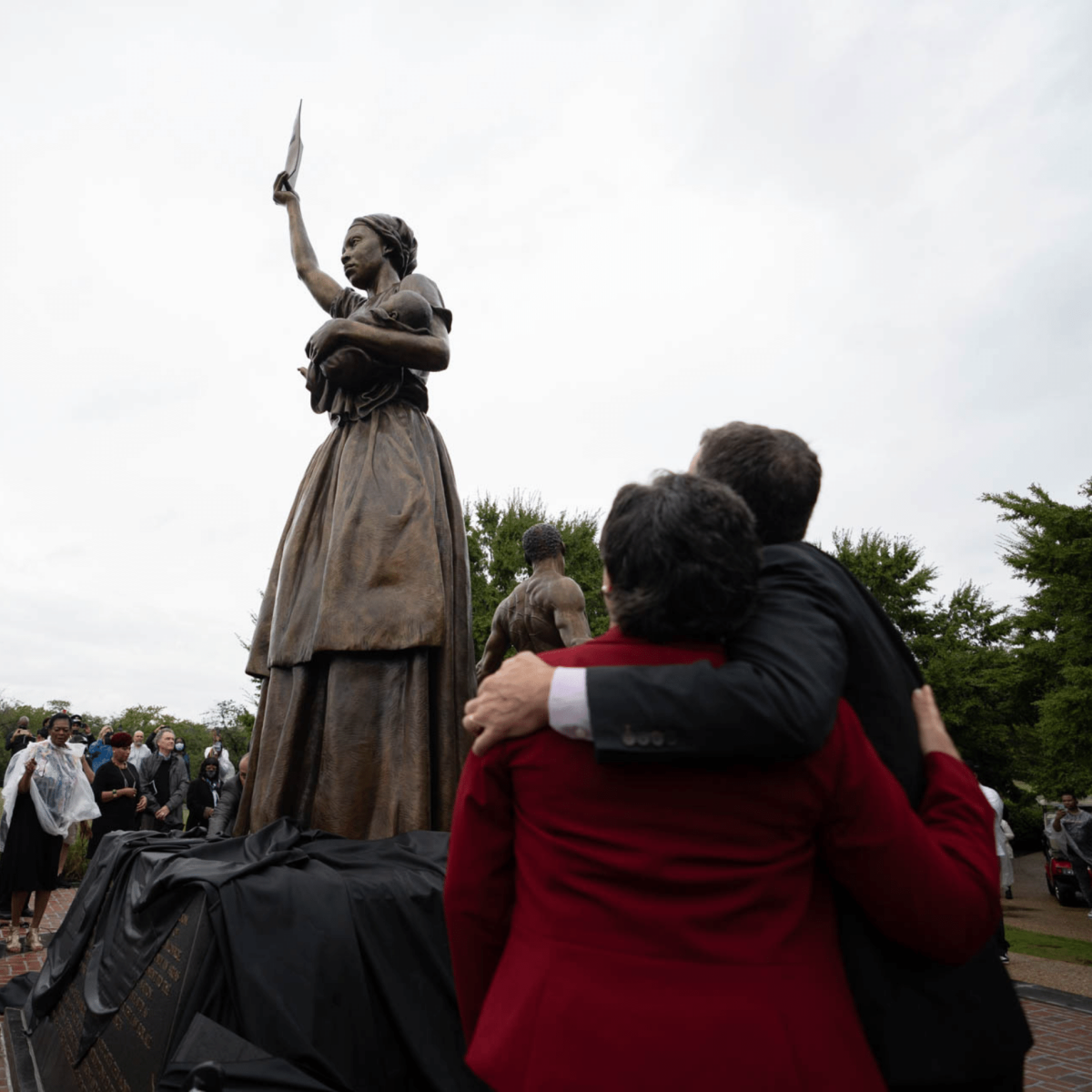 Two people standing next to the Emancipation and Freedom Monument in Richmond, VA with arms around each other