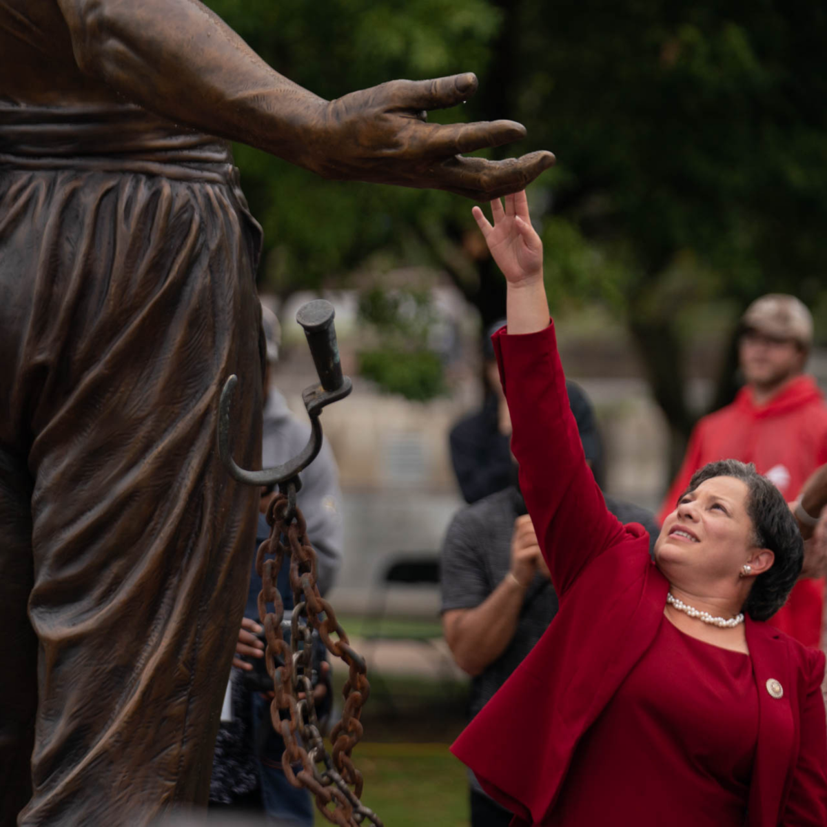 A woman touching the hand of the freed male slave statue depicted in the Emancipation and Freedom Monument in Richmond, VA
