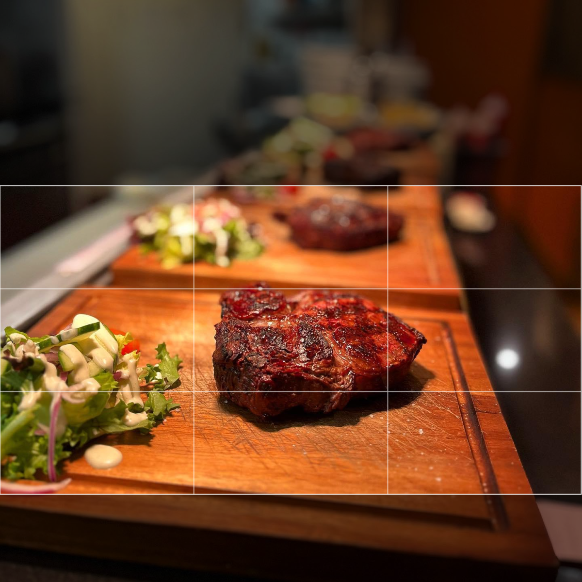 Freshly grilled steak on wooden chopping board with side salad at Argento