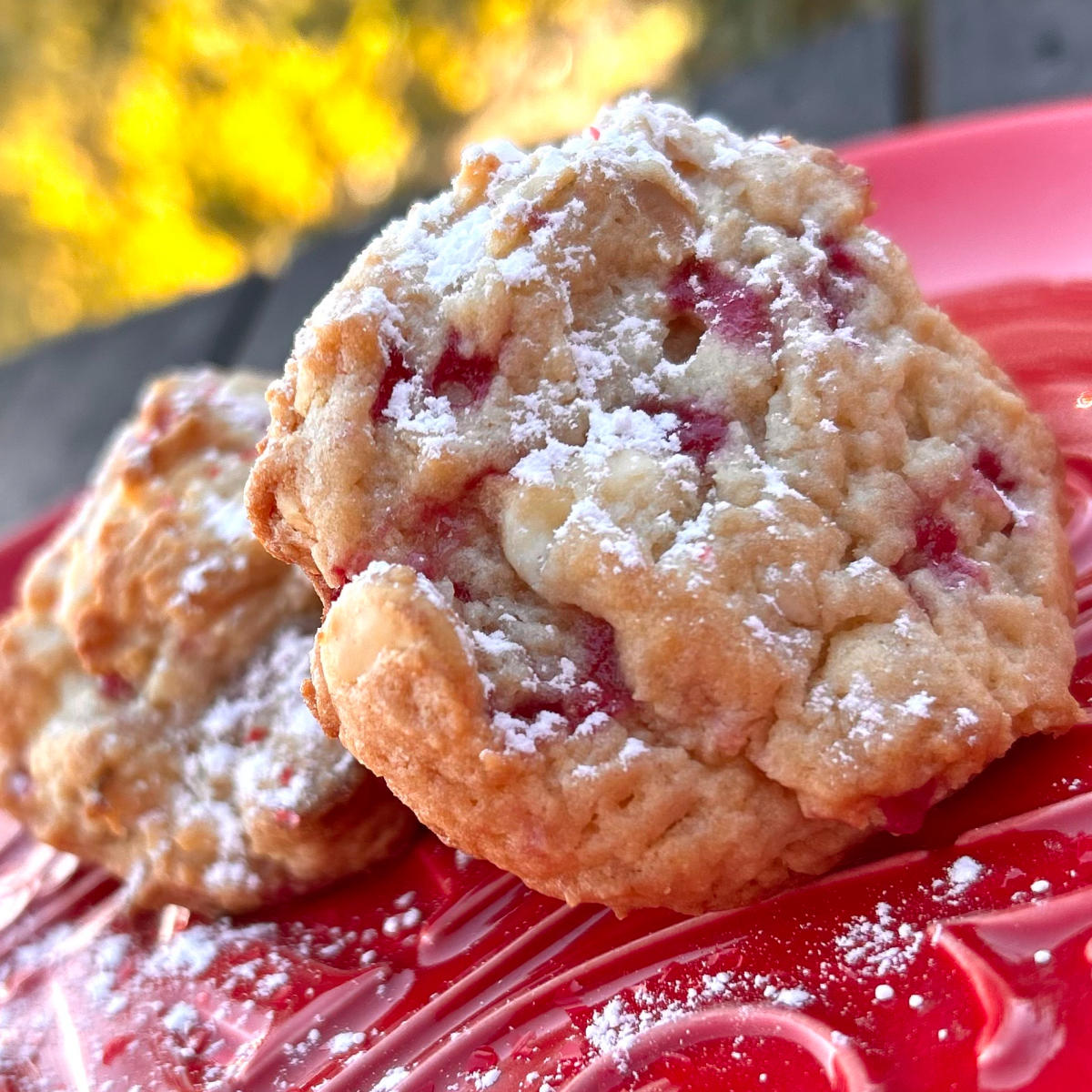 Two raspberry cheesecake cookies on a red plate