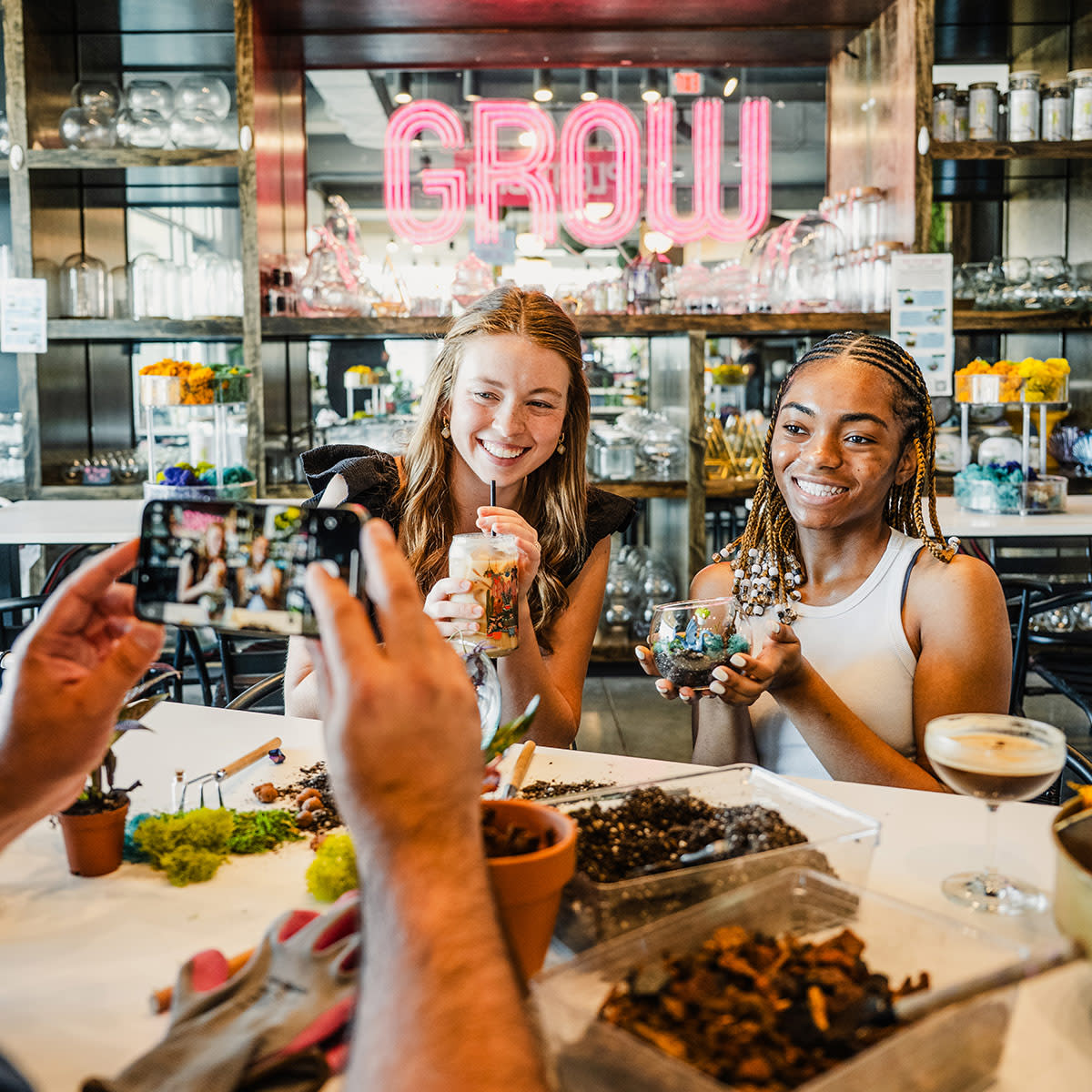 Two young women take a photo with their terrariums they built at GROW Plant Bar.