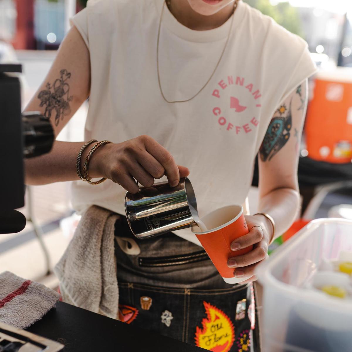 A worker pours steamed milk into a coffee cup at Pennant Coffee.