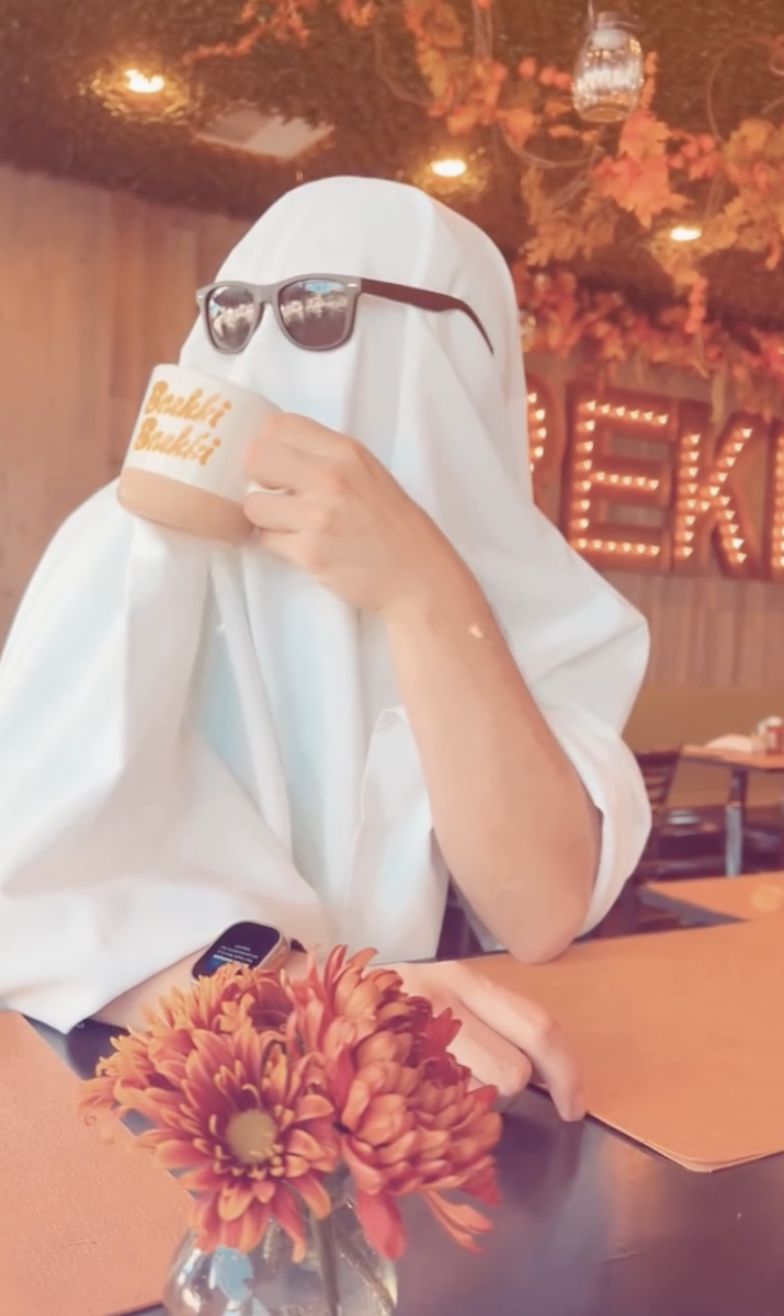 A screenshot showing a person dressed up as a ghost sipping on a beverage at Brekki Brekki.