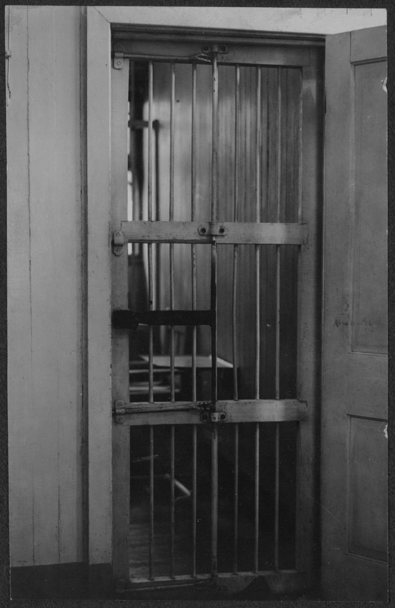 Photograph of a prison cell in Occoquan Workhouse seen through door with bars.
