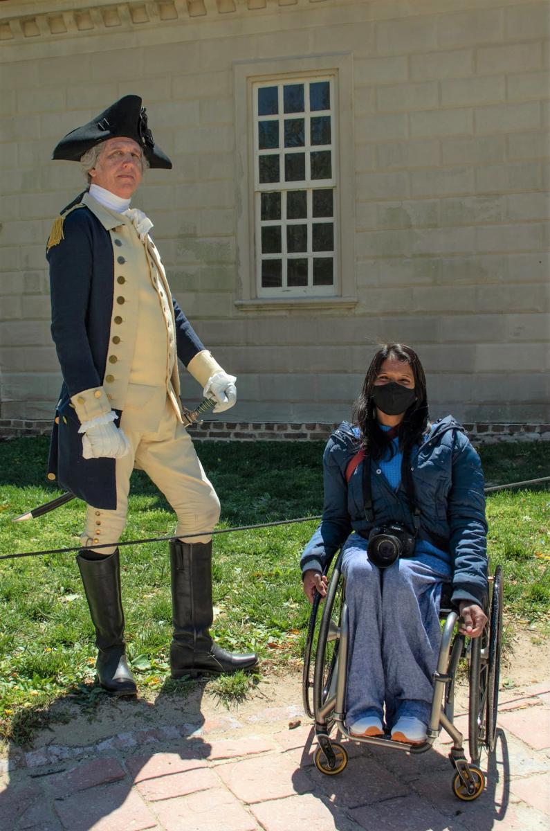 Wheelchair user posing in a photo with a George Washington reenactor in front of Washington's home, Mount Vernon