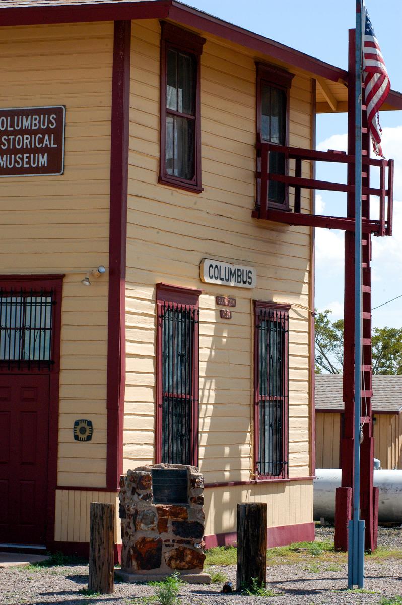 Exterior of the Columbus Historical Museum, featuring a two-story yellow building with red trim, a visible sign, and an American flag.