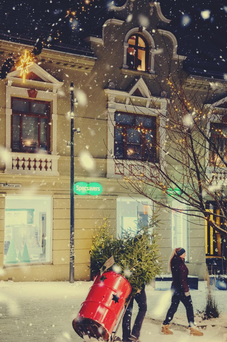 To jenter som drar et juletre i ei rød tønne gjennom gågata i Sarpsborg. Foto.