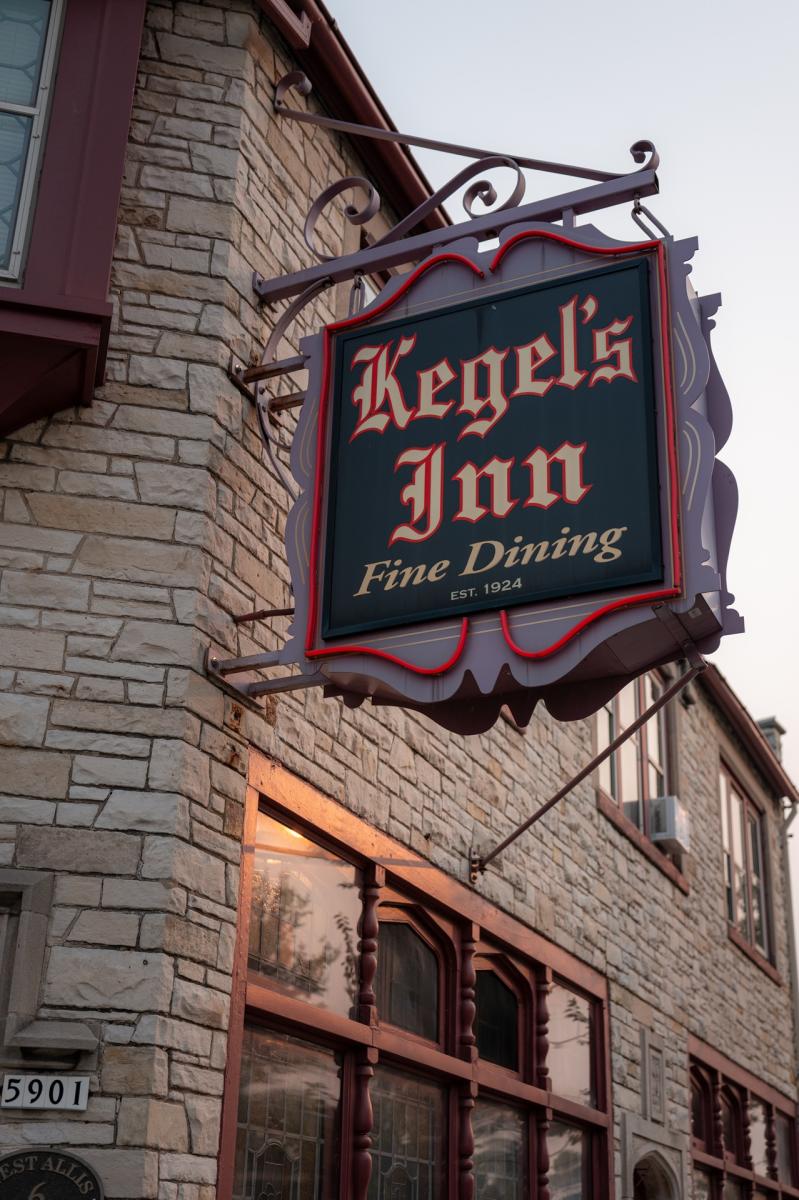 The historic Kegel’s Inn sign hangs above the stone exterior of the Milwaukee restaurant, featuring ornate lettering and red neon trim.