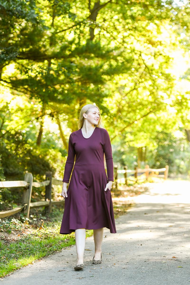 Purple long sleeve dress that hits under knee on a blond haired woman walking down a path