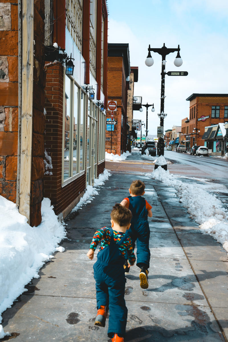 two kids run on a main street