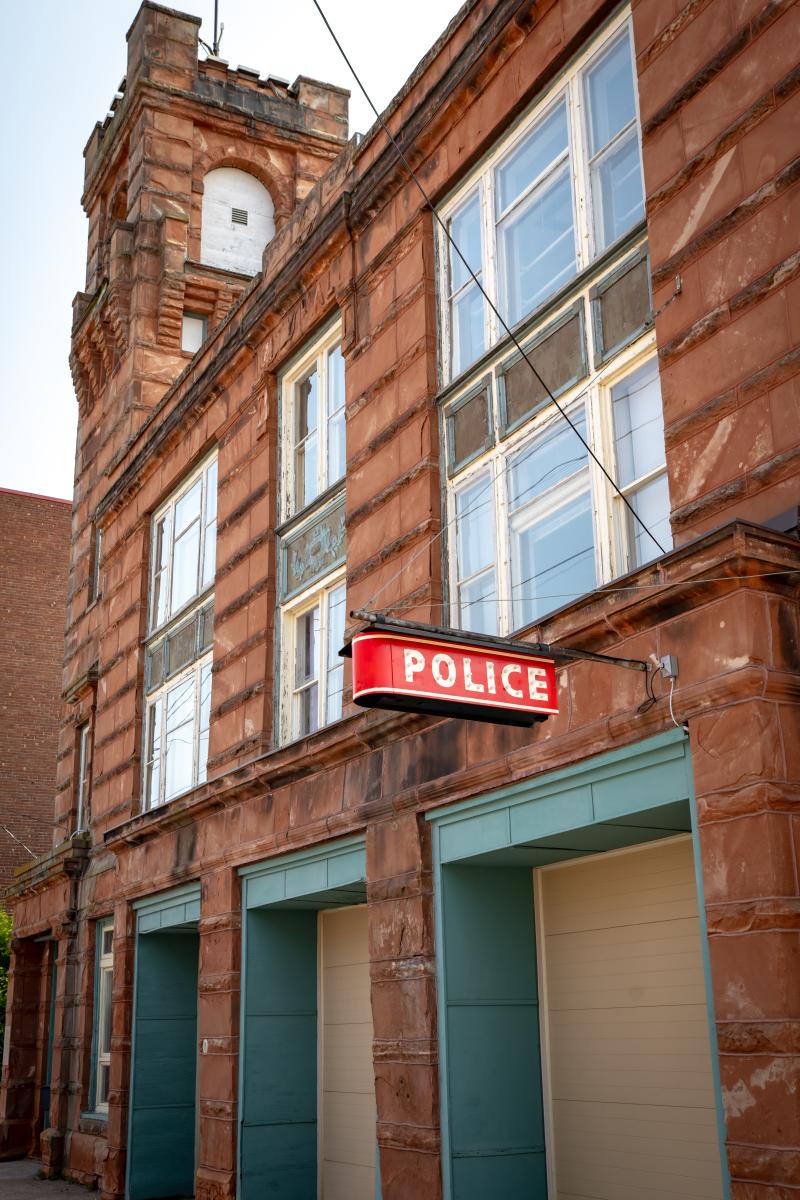sandstone building with a neon police sign