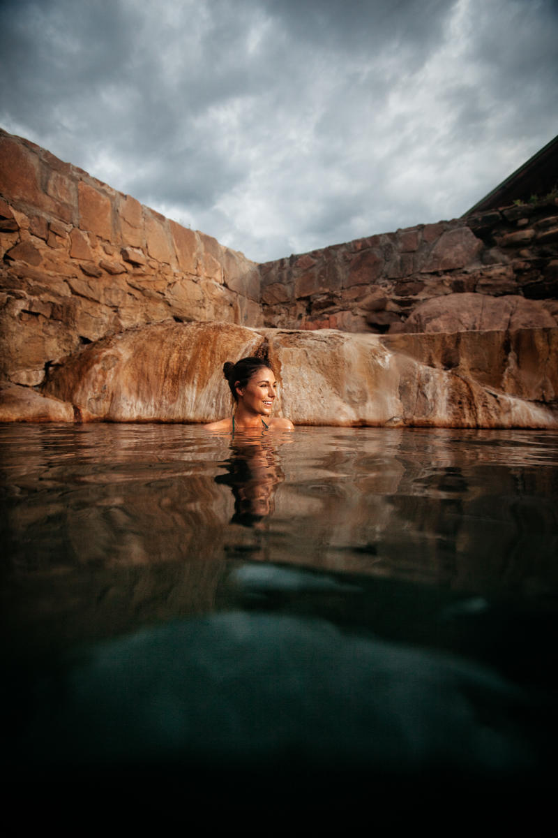 A person relaxing in a natural hot spring surrounded by natural rock edges.