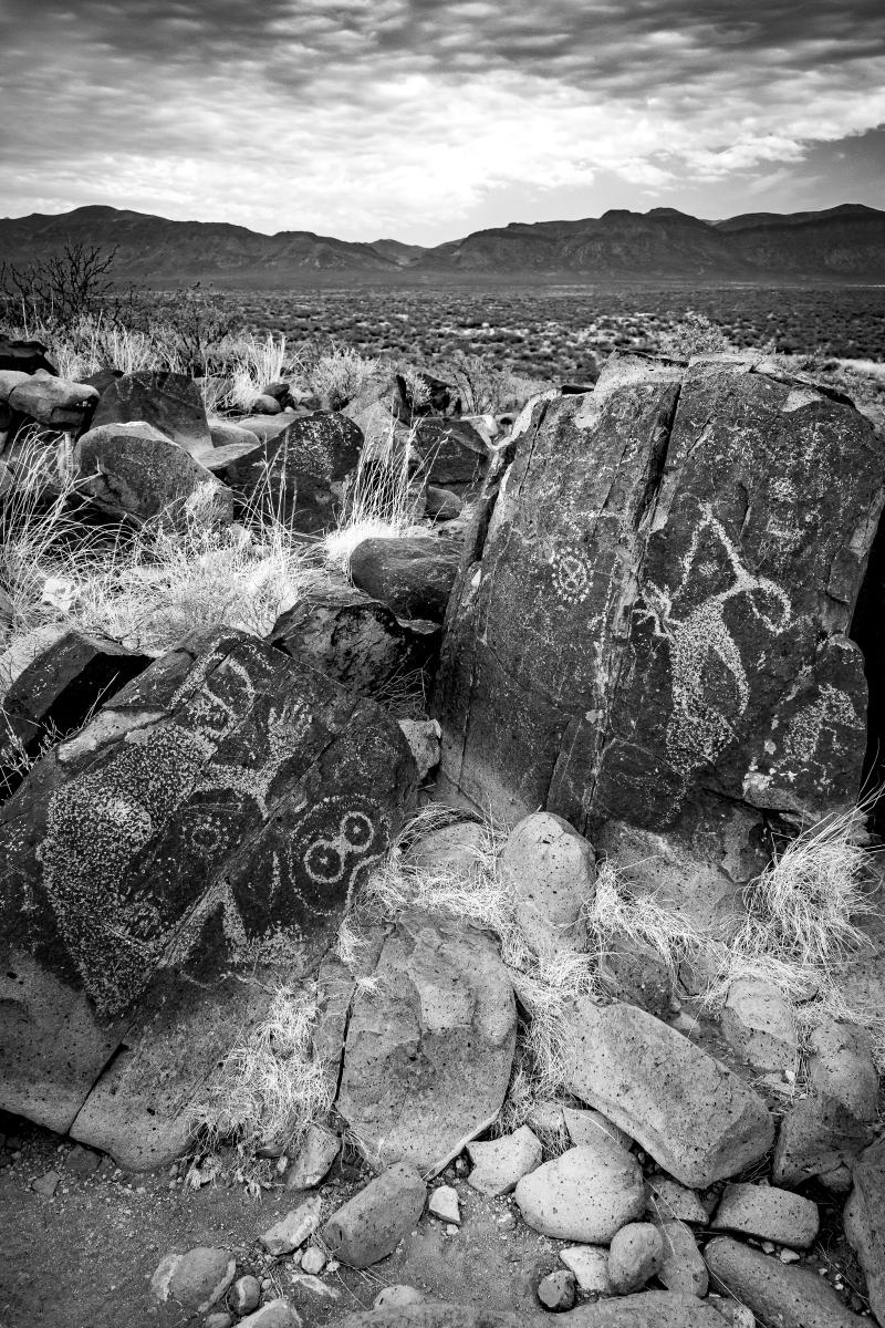 Jornada Mogollon–style petroglyphs on scattered boulders along a rocky ridge in southern New Mexico.