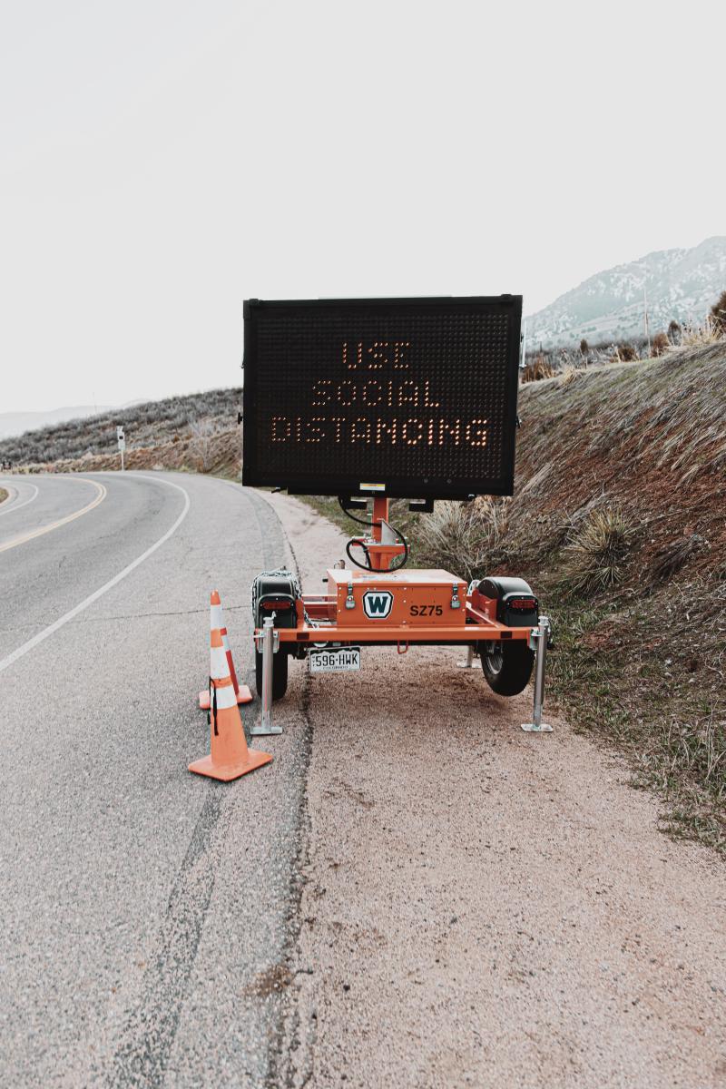 A light up road sign that says Use Social Distancing on the side of a highway