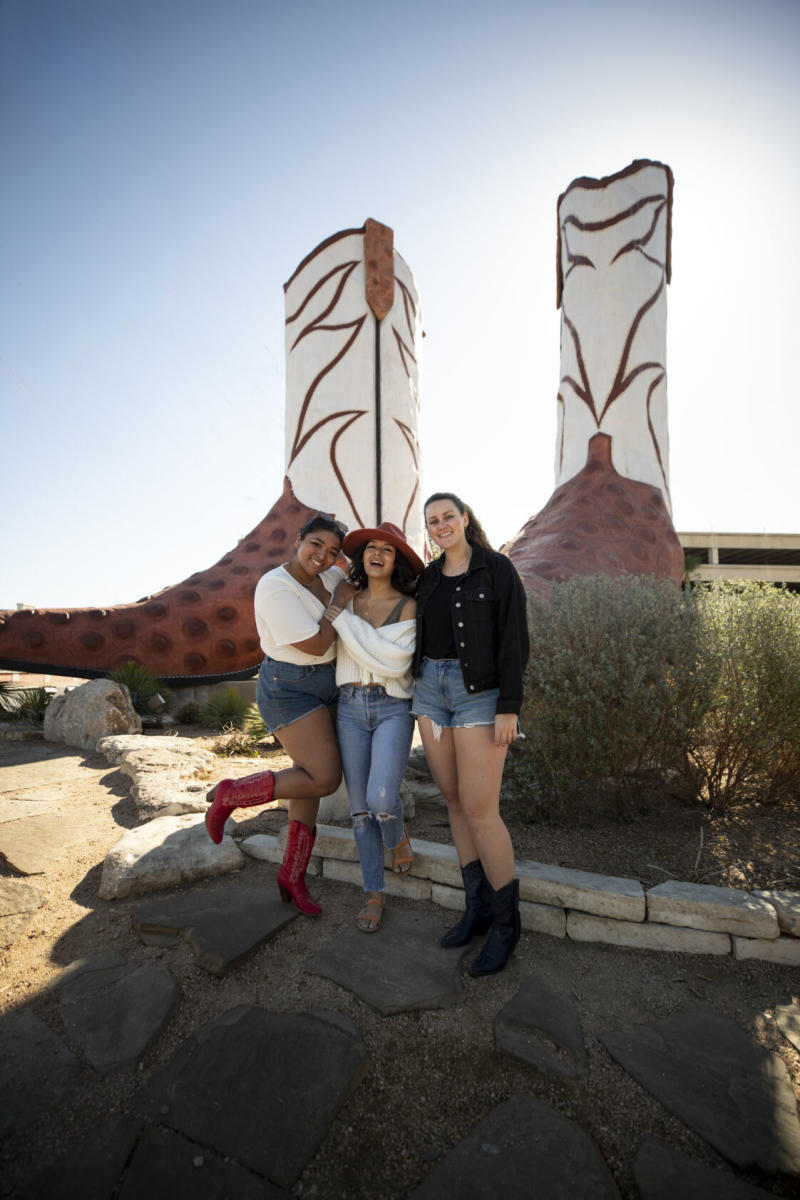 Three girls in front of cowboy boots sculpture