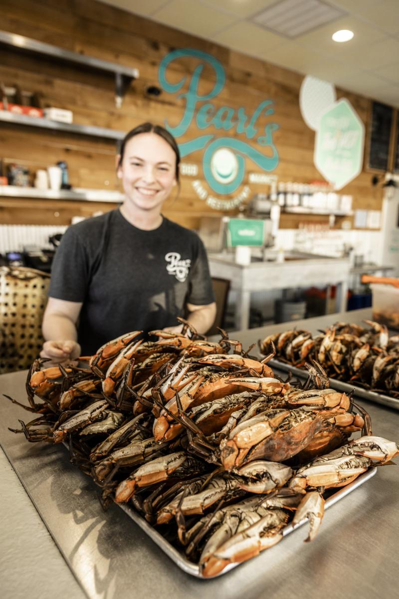 A woman displays a tray of cooked crab at Pearl's Seafood.