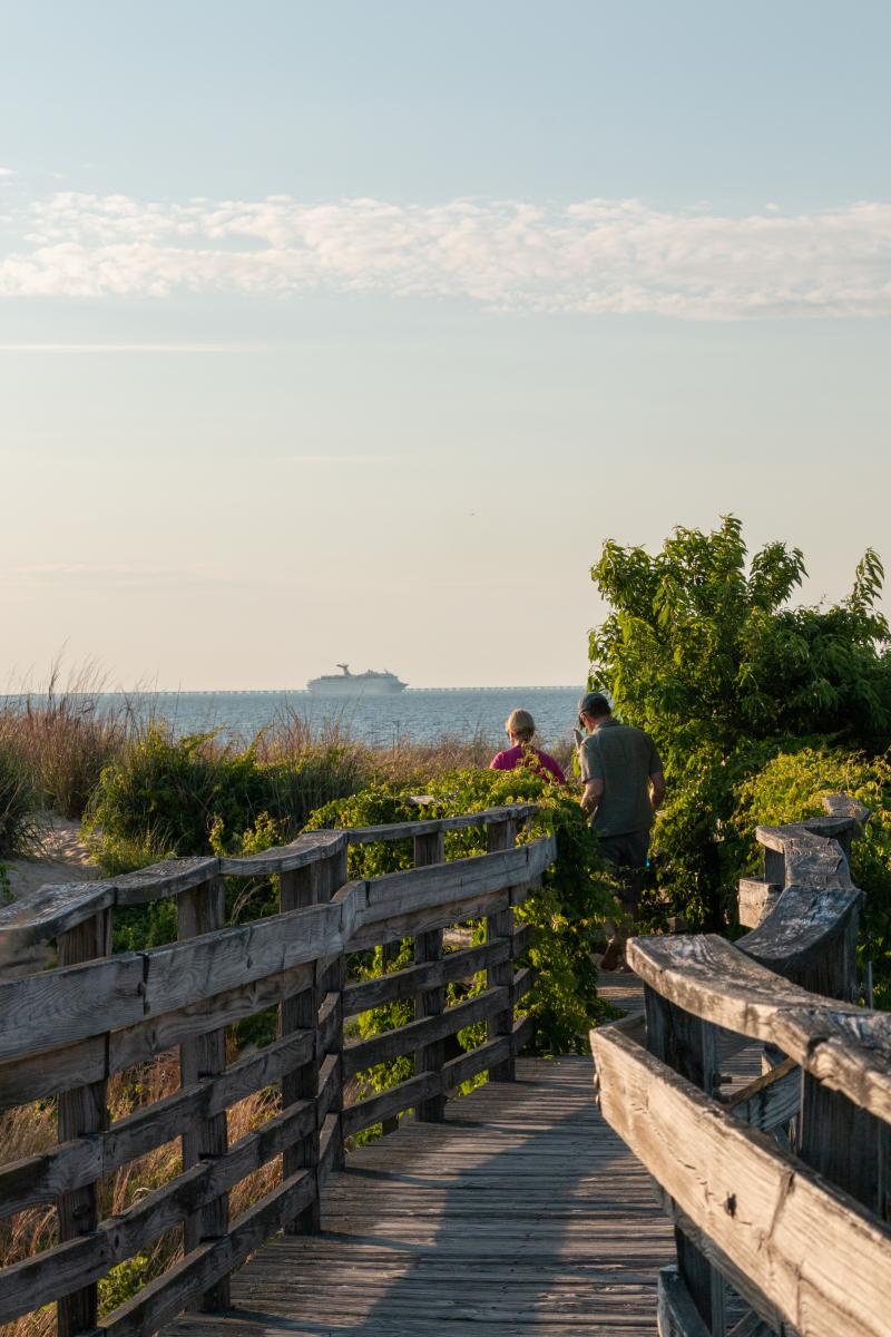 people walking through a wooden beach ramp
