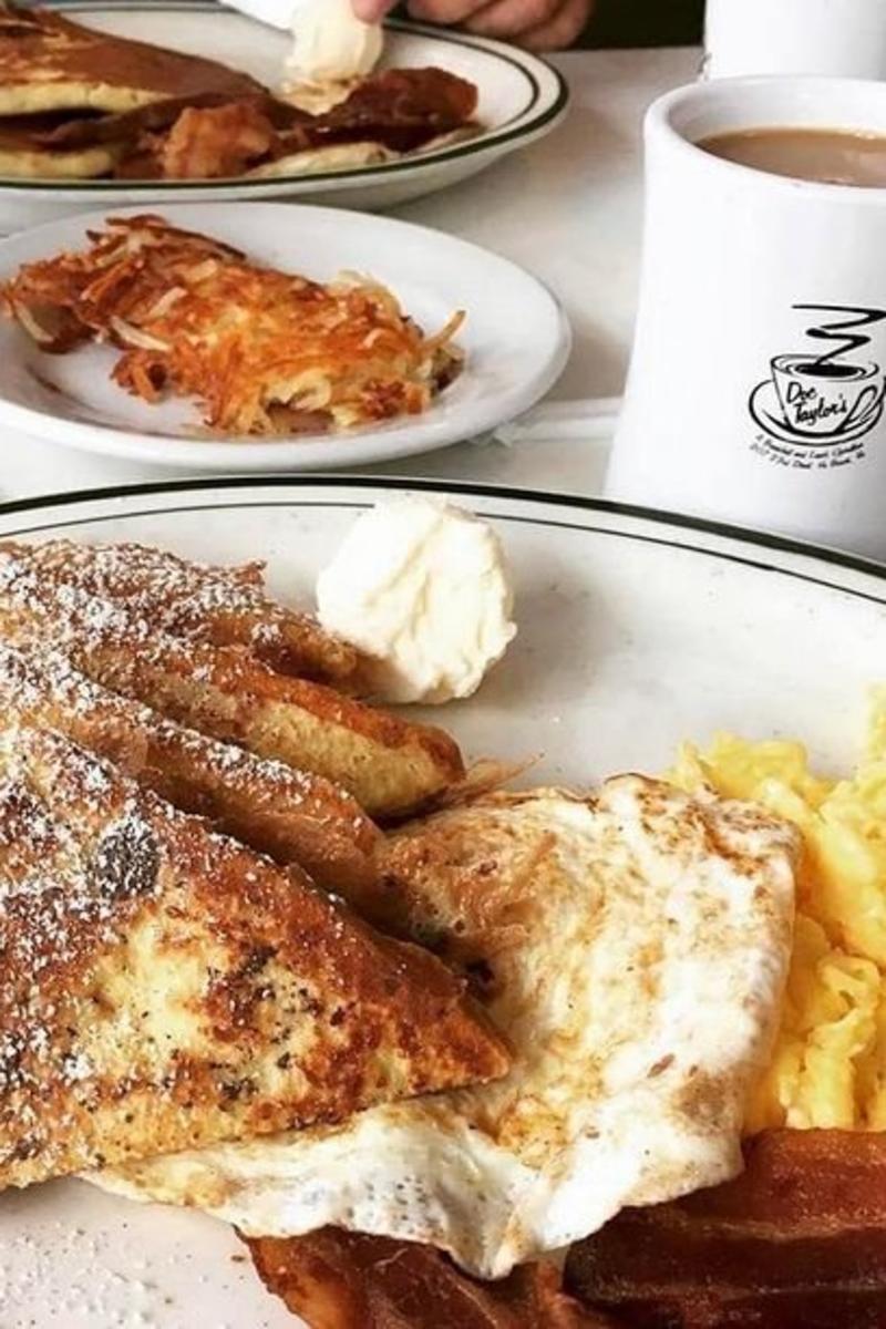 french toast, eggs, bacon on a plate with a cup of coffee and breakfast foods in the background