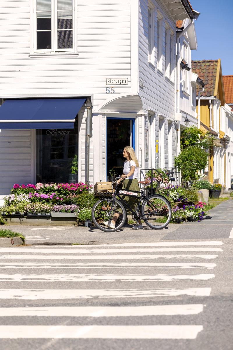 Kvinne på sykkel foran Annemones blomster i Posebyen