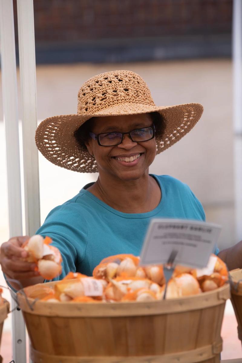 A woman smiles while picking garlic from a basket at Orie's Garlie Festival
