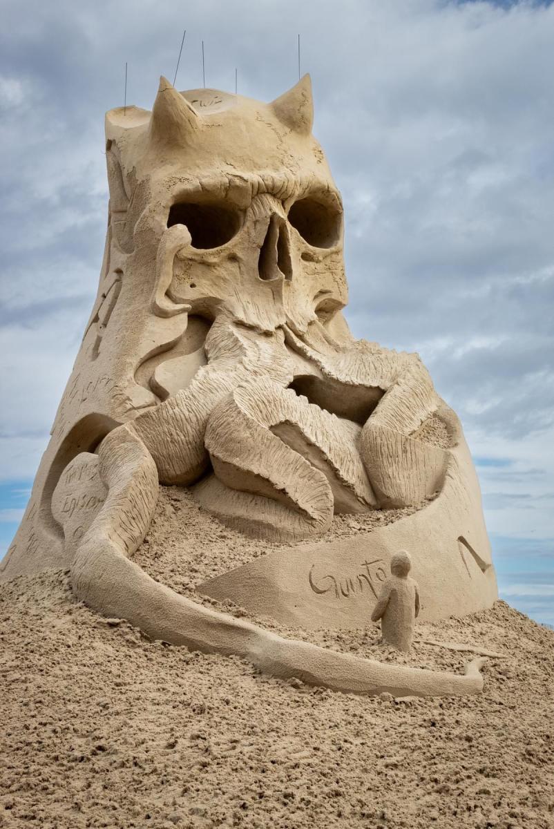 Sand sculpture of a skull with horns. Out of the mouth are wrapping monster tendrils