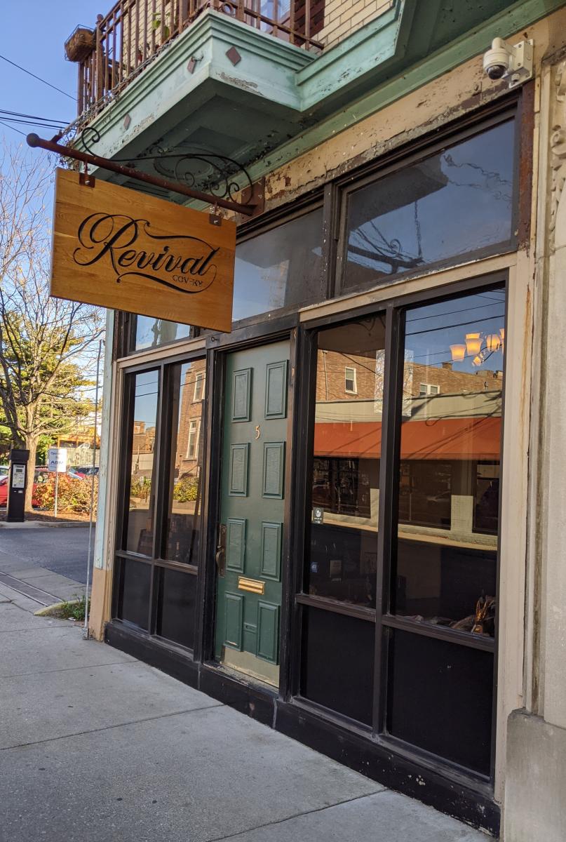 The storefront to Revival Vintage Spirits with a green door and wooden sign