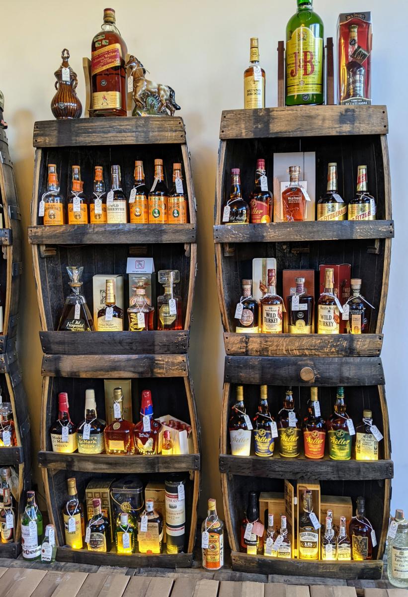 Two tall shelves holding dozens of bottles of vintage bourbon at Revival Vintage Spirits