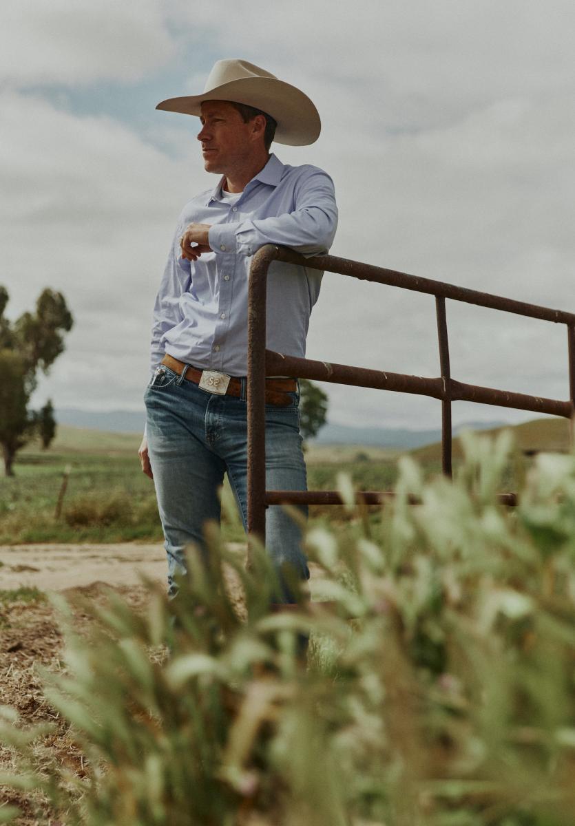 Daniel Sinton stands next to gate on his ranch.