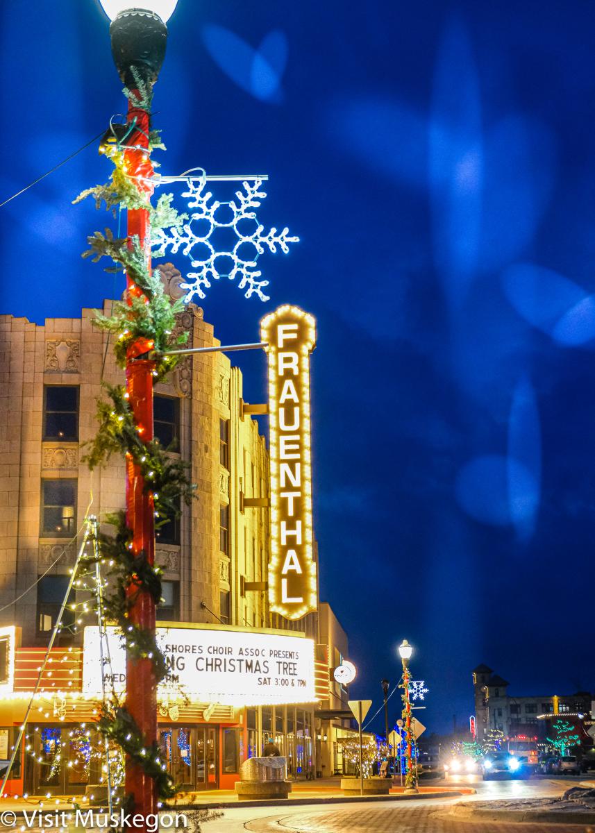 Historic theater in moorish style is lit agains dark winter blue sky. Sign reads Frauenthal. A festooned lamppost is in the foreground topped with with large snowflake