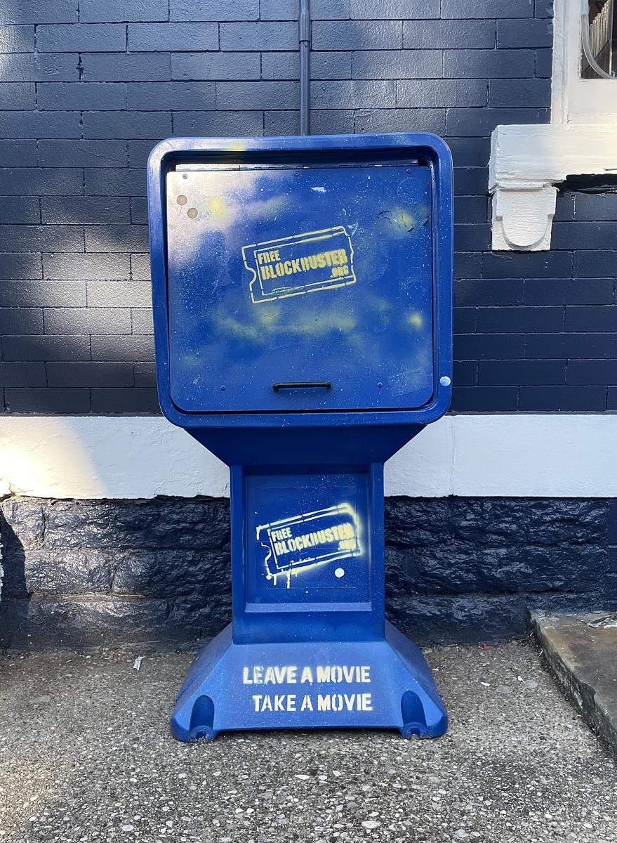 Image is of a freestanding "Blockbuster" box that say's "Leave a movie, take a movie".