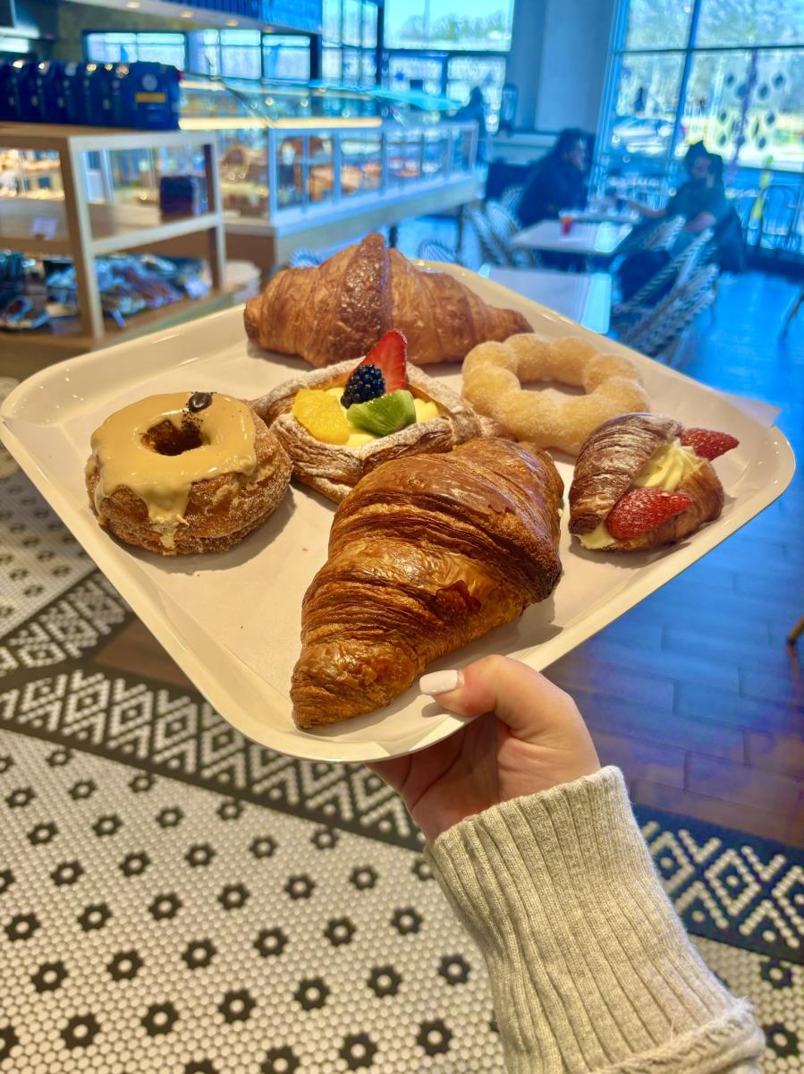 A plate with cronuts, croissants, and a fruit tart.