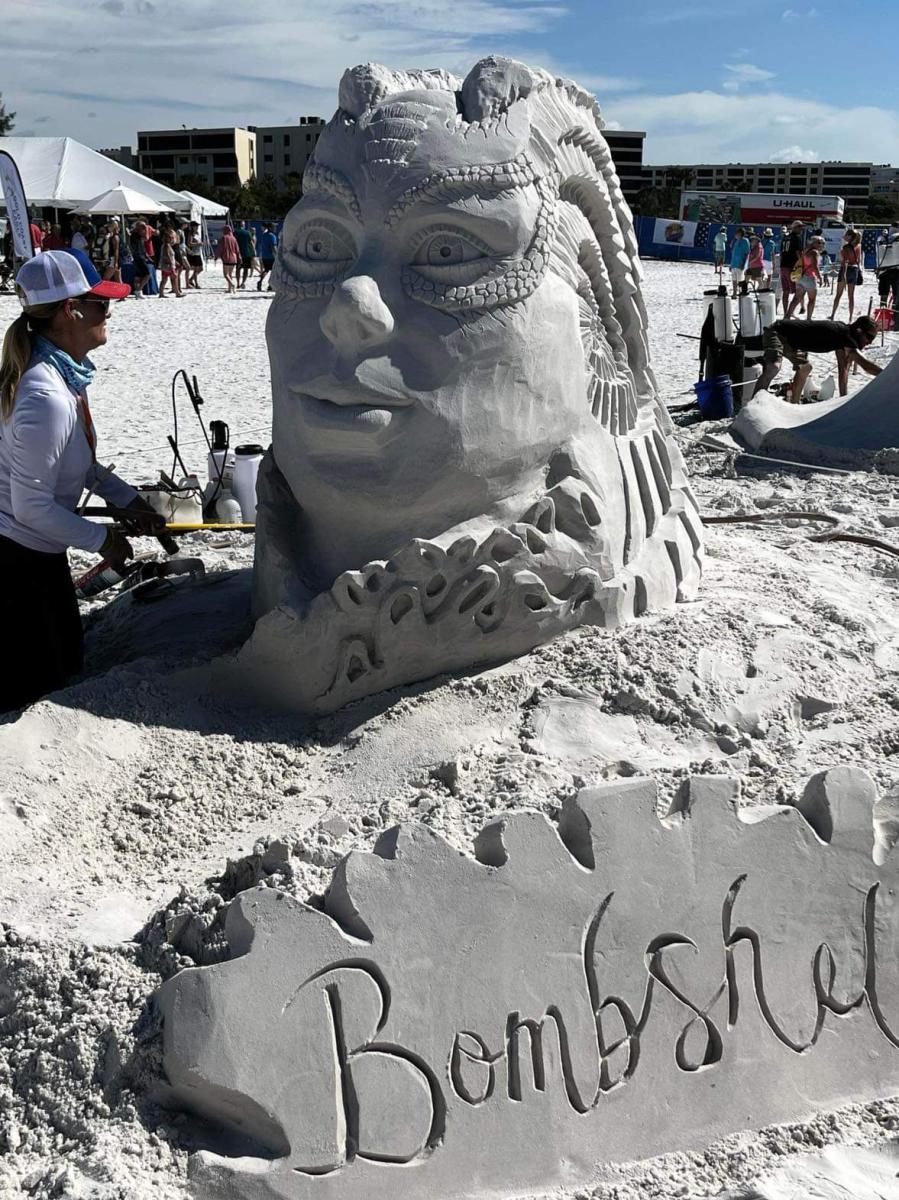Sand sculpture showing a woman's face with serpentine features and text that says, "Bombshell."