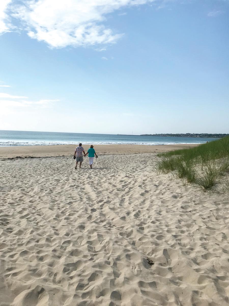 couple holding hands walking on the beach
