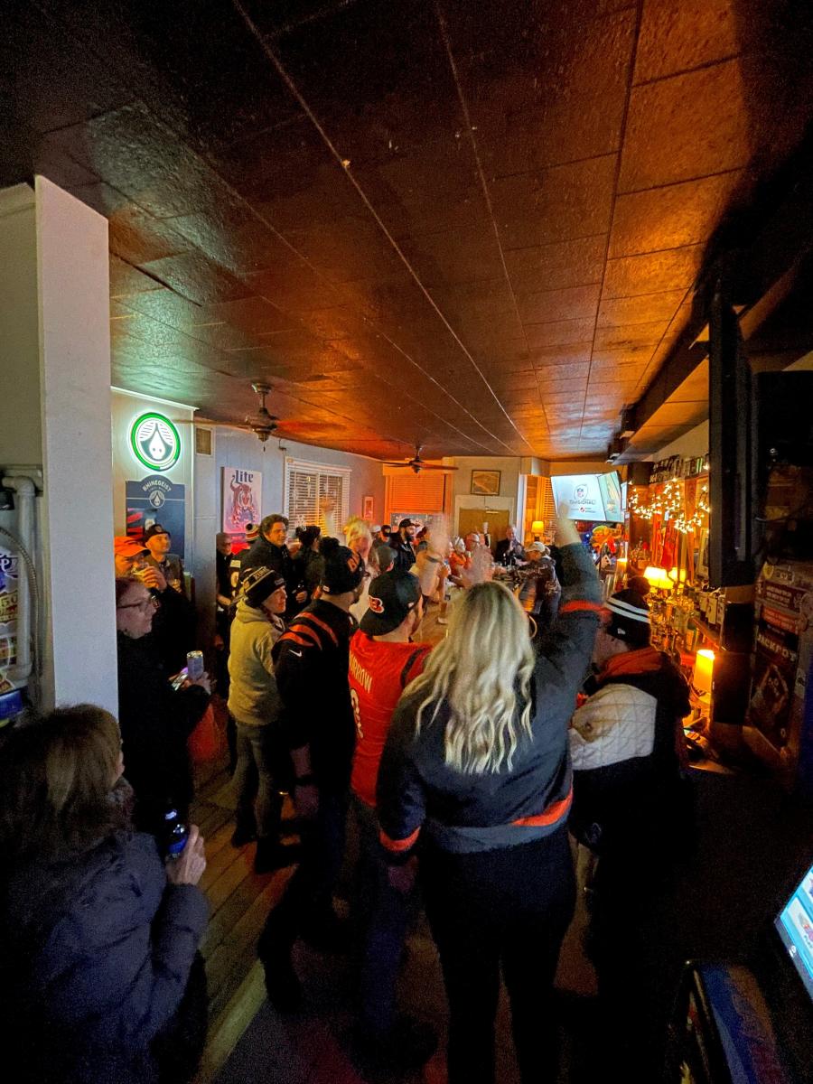 Inside the bar with patrons dressed in the Cincinnati Bengals gear watching the game.