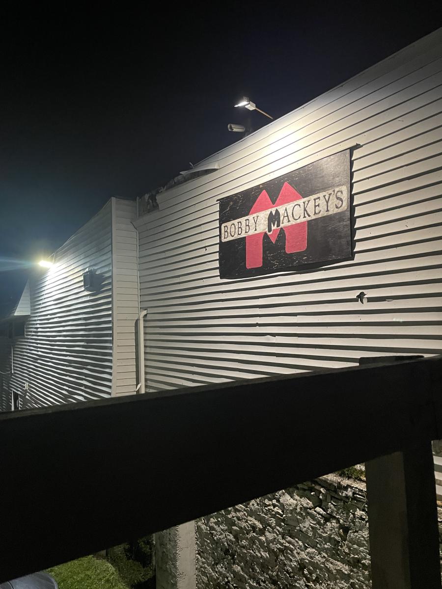 The image is of the Bobby Mackey's sign on their building in at night with a light shinning onto it.
