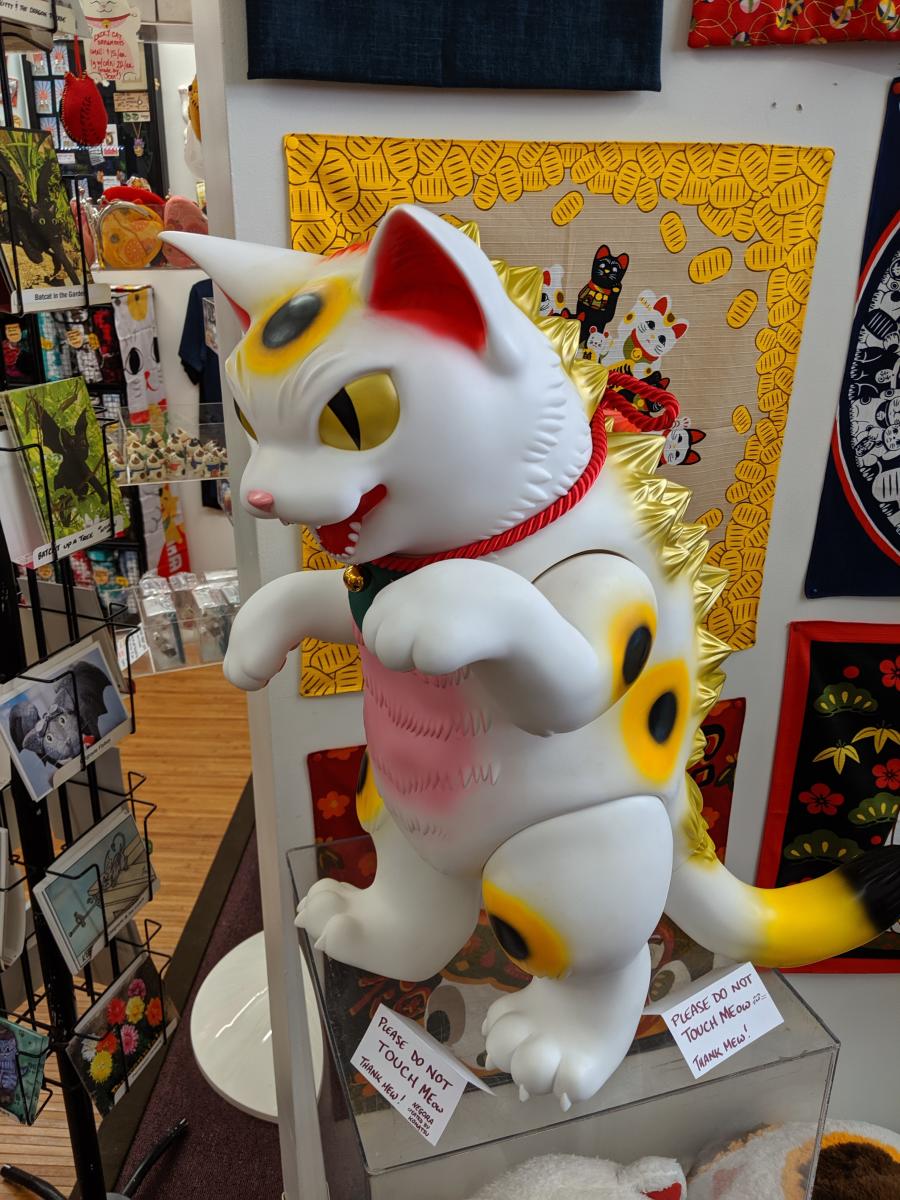 A large white, pink, and gold Lucky Cat statue with a red collar at the Lucky Cat Museum in Cincinnati, Ohio