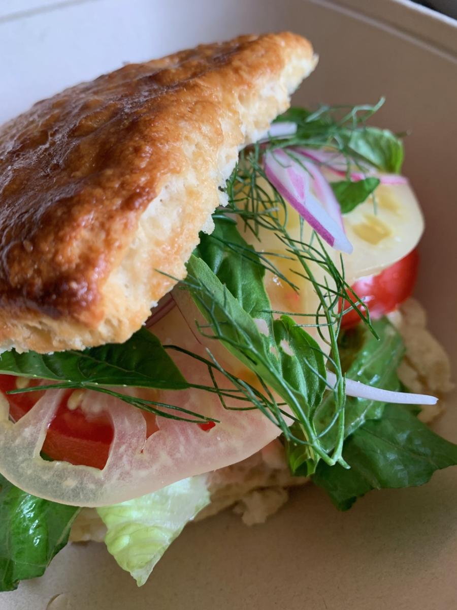 A freshly-made sandwich from Kolache Republic is topped with fresh tomato and greens.