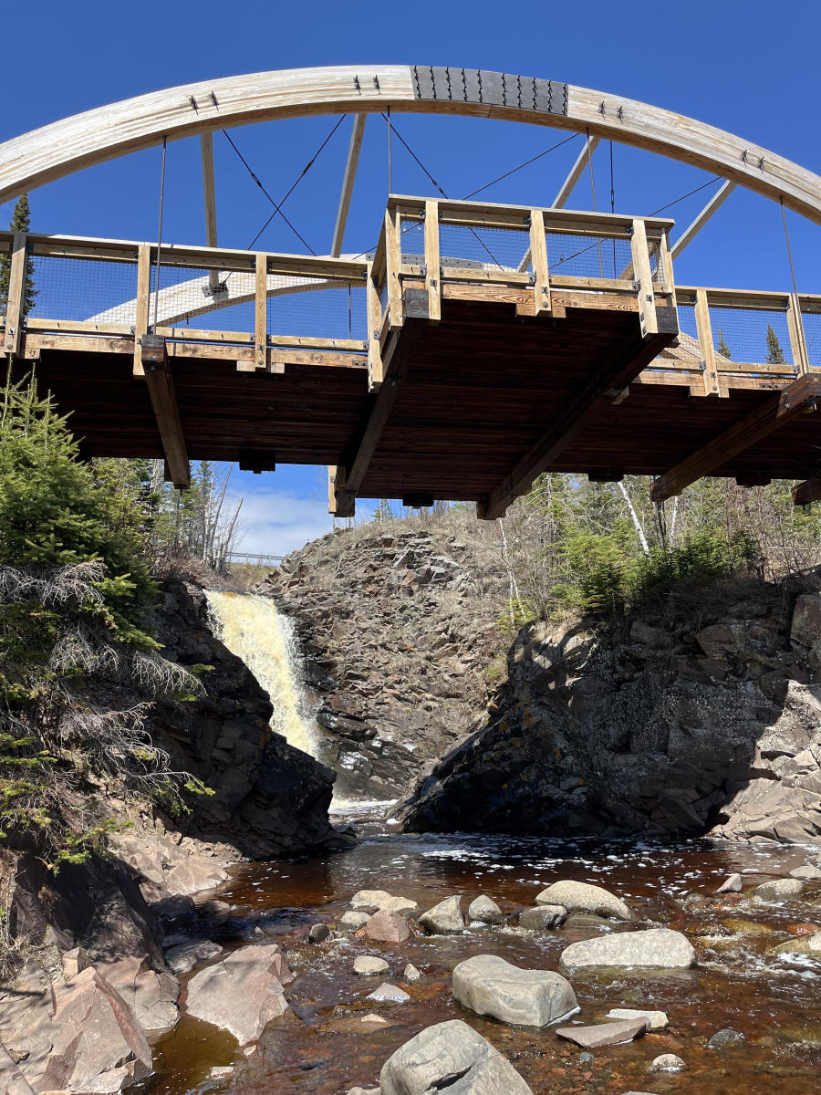 A river flowing down with a bridge going over it.