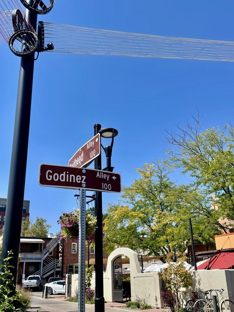 Wire light instillation with road name sign that says Godinez alley