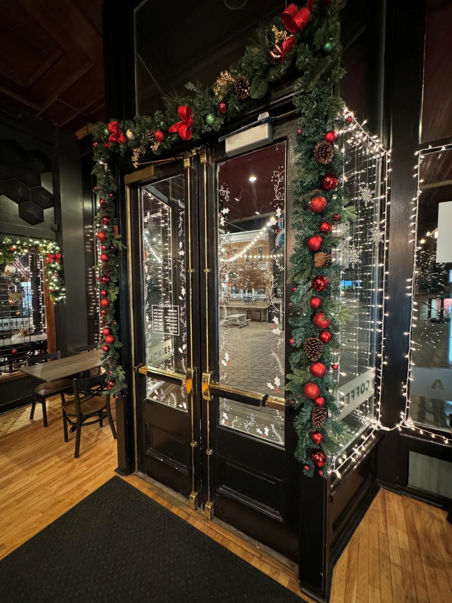 An image of coffee shop doors with garland and red ornaments