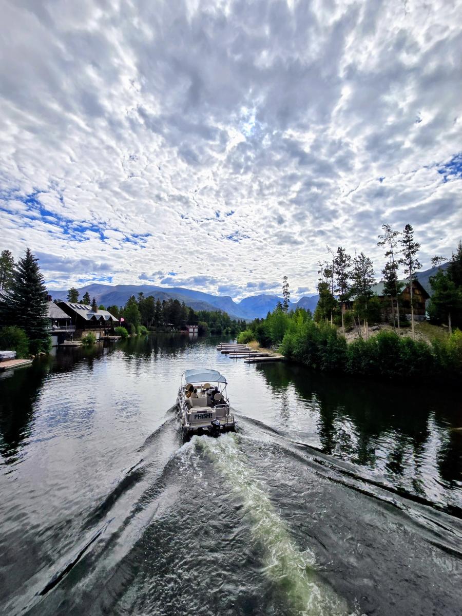 Photo shows a boat passing through the channel between Shadow Mountain Reservoir and Grand Lake with Mount Baldy in the background